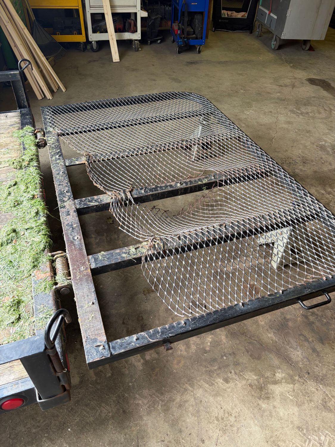 Trailer gate before repair, with damaged expanded metal mesh